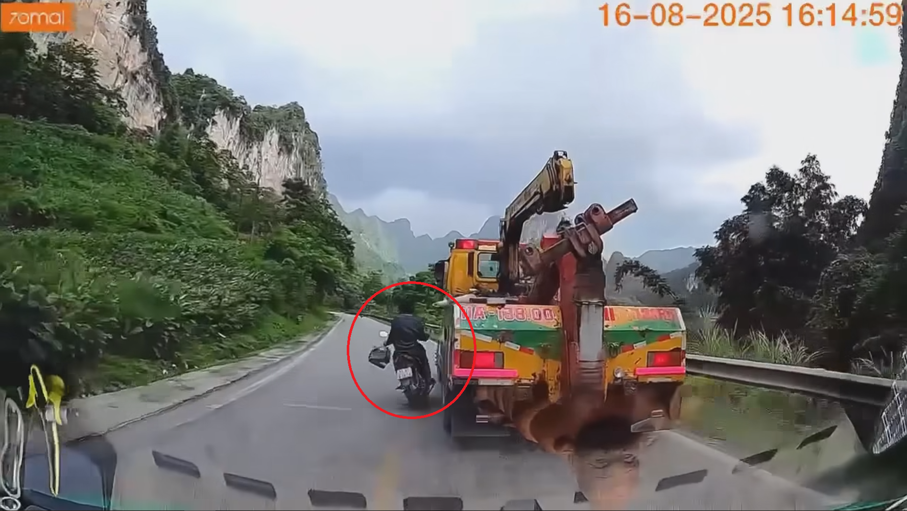 Lái xe máy một tay, tay kia cầm lồng chim, thanh niên va vào xe cẩu may thoát nạn