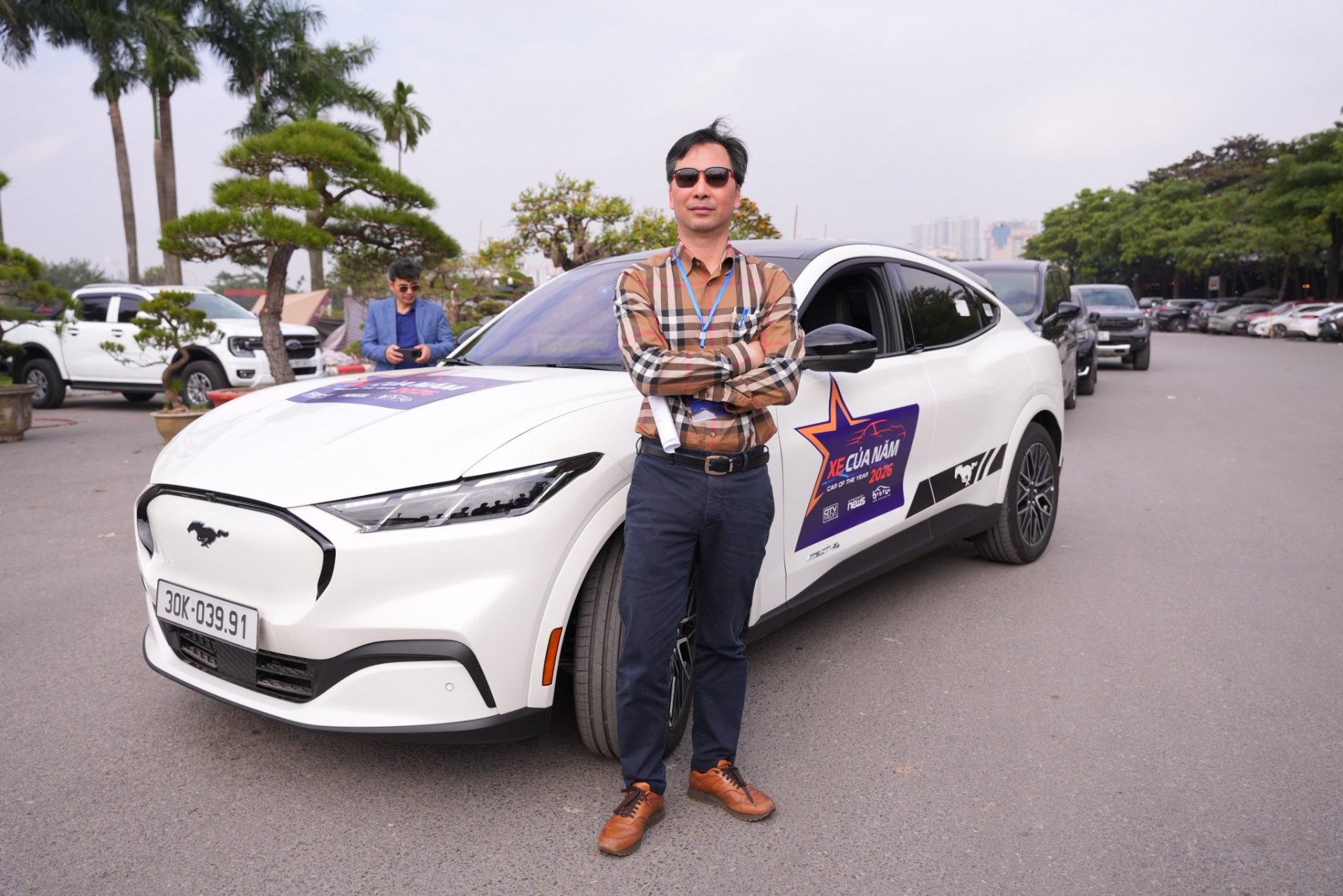 Xe Của Năm 2026: Các giám khảo nói gì về Ford Mustang Mach-E? Ông Đàm Hoàng Phúc đứng cùng chiếc Ford Mustang Mach-E