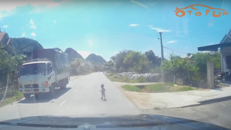 Em bé bò trước đầu xe trên quốc lộ giữa trưa nắng