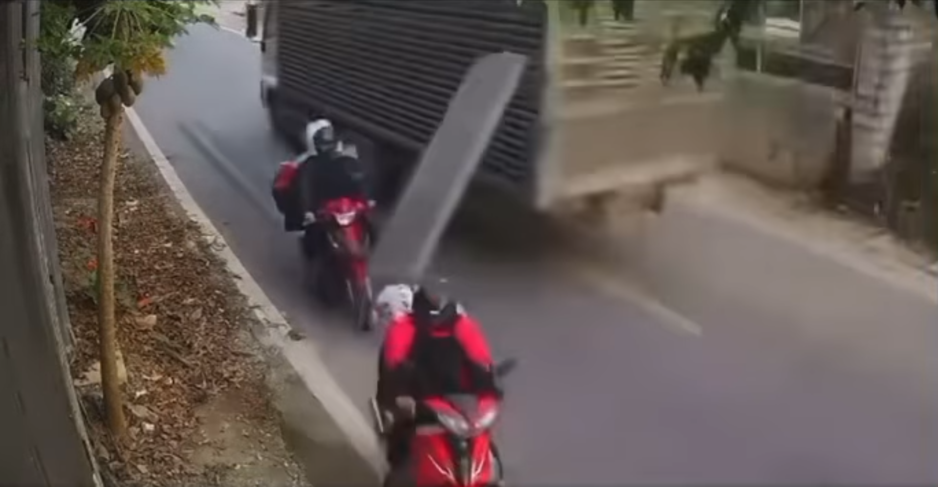 Tông trúng miếng nhôm bên hông xe tải bị rời ra, người lái xe máy ngã ra lề đường