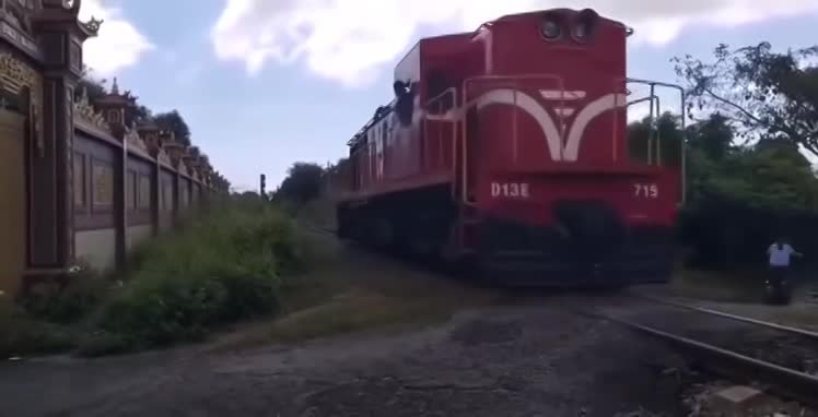 'Thót tim' cảnh bé gái đi xe điện vượt qua đường ray đúng lúc tàu hỏa gần đi tới