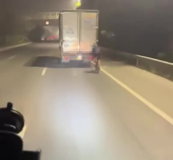 Người đàn ông đi xe đạp 'ngang nhiên' bám đuôi xe tải ở cự ly gần