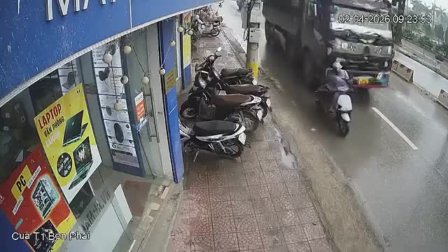 Xe tải chèn ép xe máy đang đi sát lề đường, khiến người và phương tiện ngã ra đường
